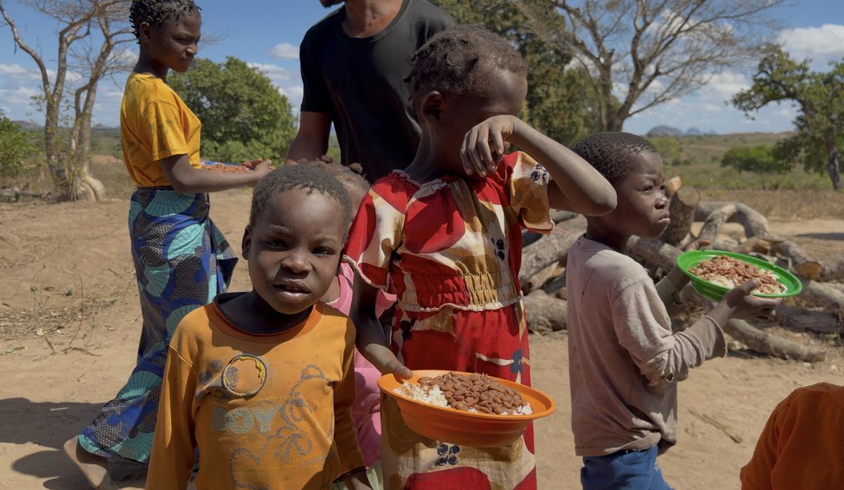 Crianças segurando pratos com arroz e feijão no dia da distribuição